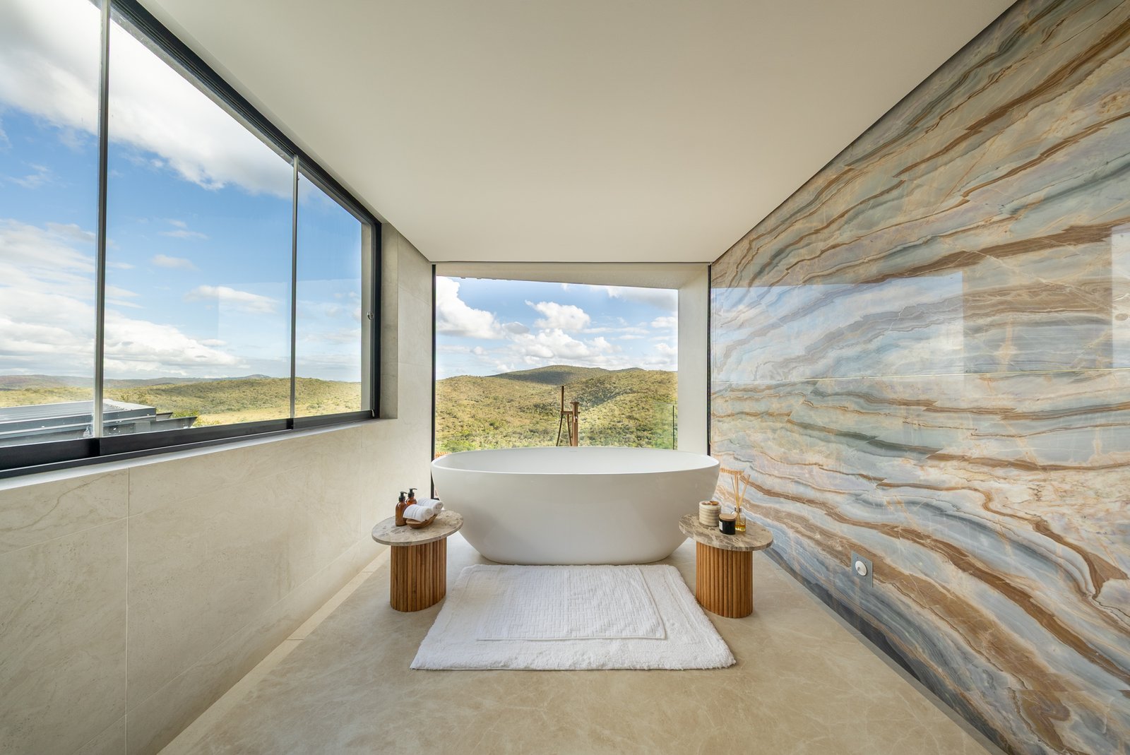 Freestanding bath against a bookmatched stone wall